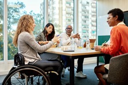 Four colleagues sitting in a meeting with the boss in a wheelchair
