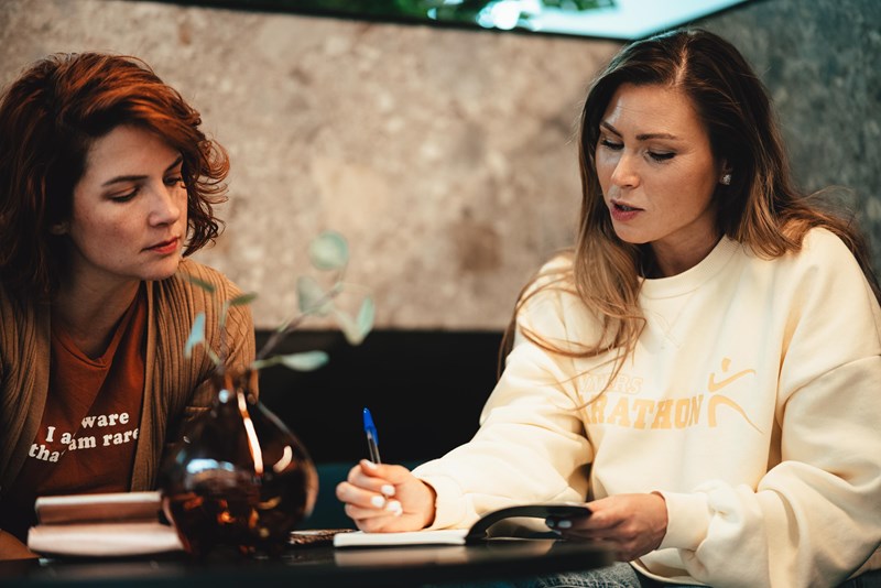 To kvinnelige studenter som sitter på kafé og jobber