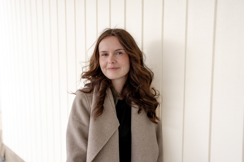 Person i yttertøy står foran lys vegg med vertikale linjer