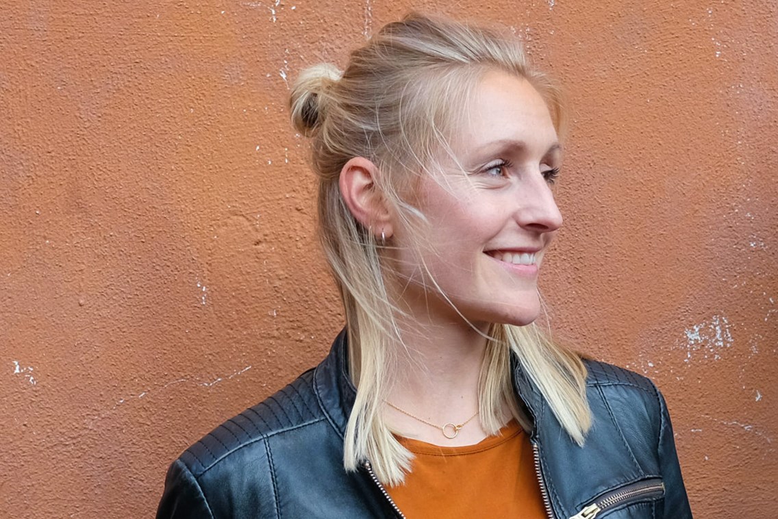 Foto av kvinne foran en murvegg.