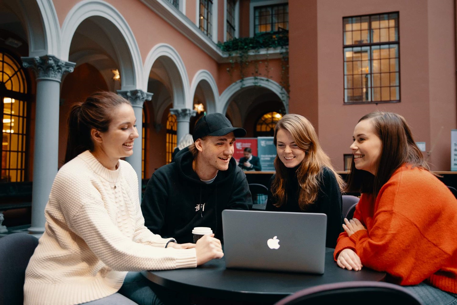 Fire studenter samarbeider foran mac på campus.