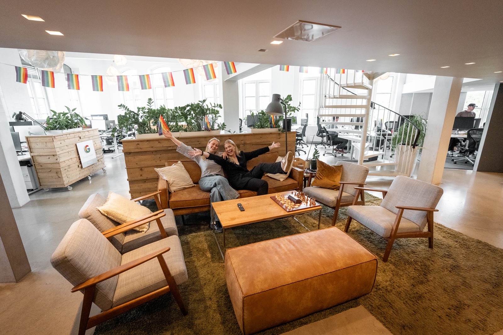 To kolleger sitter i loungeområdet på arbeidsplassen sin.