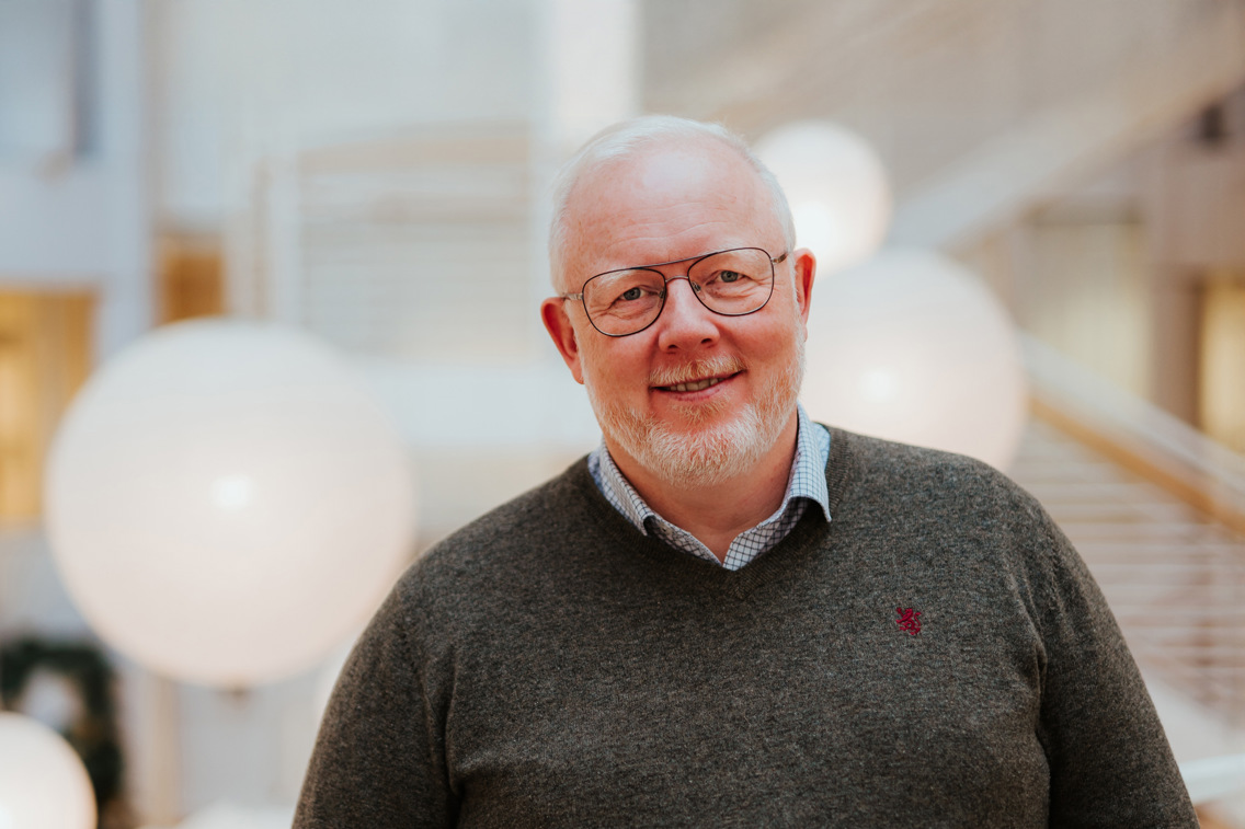 Portrett av Anders som står på campus med trapper i bakgrunnen. 