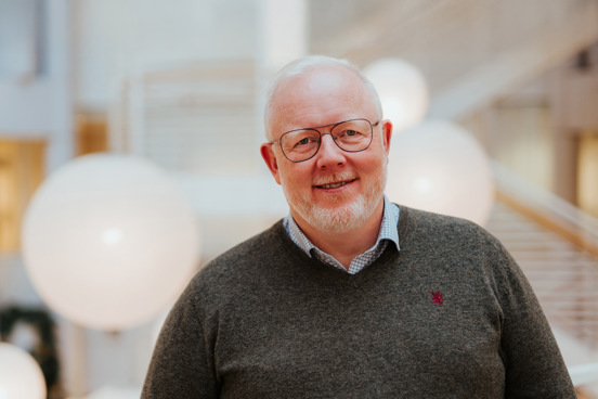 Portrett av Anders som står på campus med trapper i bakgrunnen. 