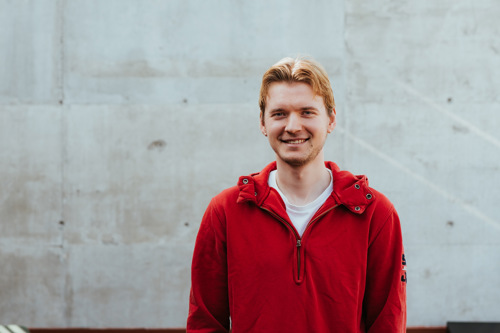 Student poserer foran vegg, bildelenke til landingsside for masterstudier.