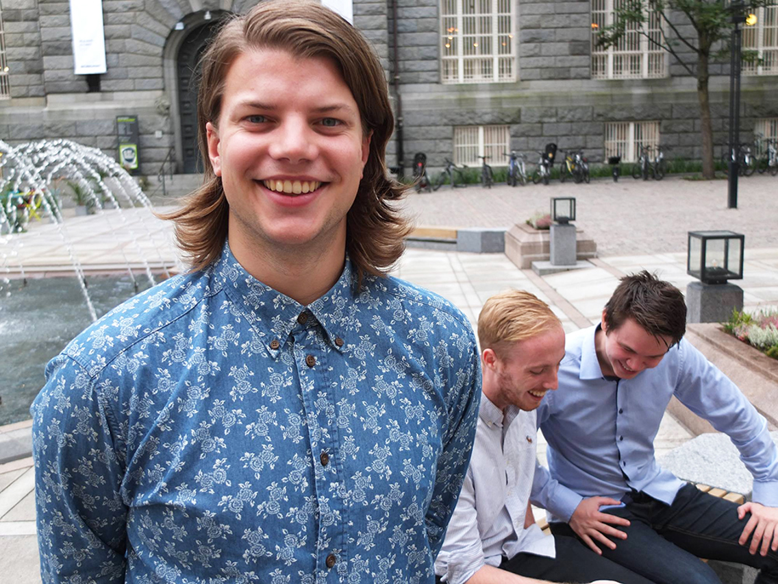 Foto av Lasse Thoresen Fadum foran to menn som ser på en mobilskjerm.