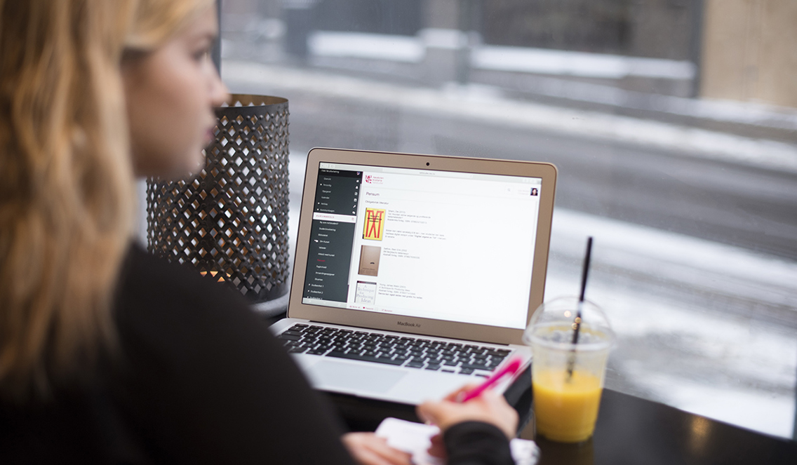 Foto av kvinne på kafé som jobber med PC.