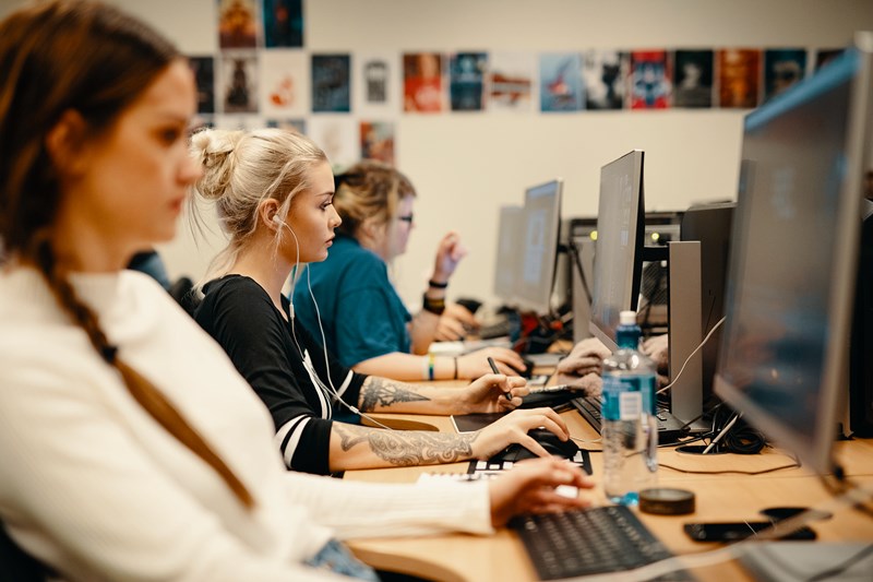 Foto av tre damer som sitter og ser på hver sin pc skjerm