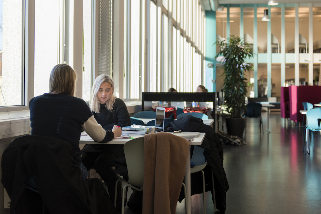 Foto av studenter som jobber ved et bord i et fellesområde.