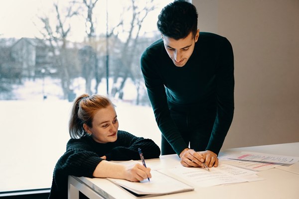 To studenter med skriveblokker som jobber kreativt sammen