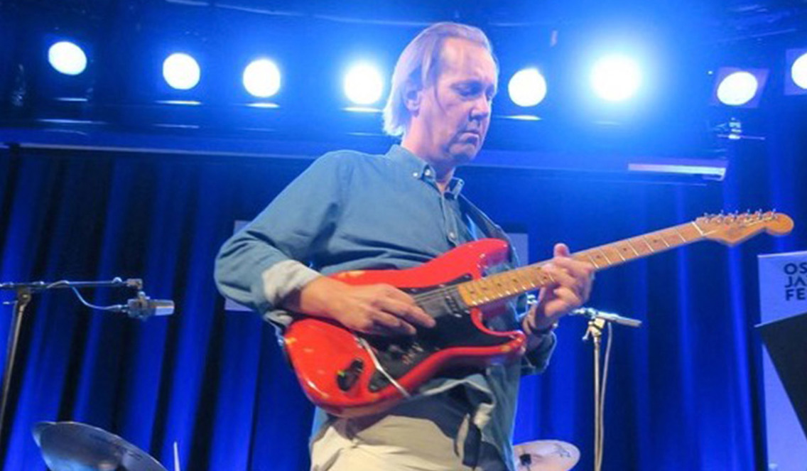 Mann med gitar på scenen.