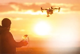 En mann som kjører drone i solnedgangen