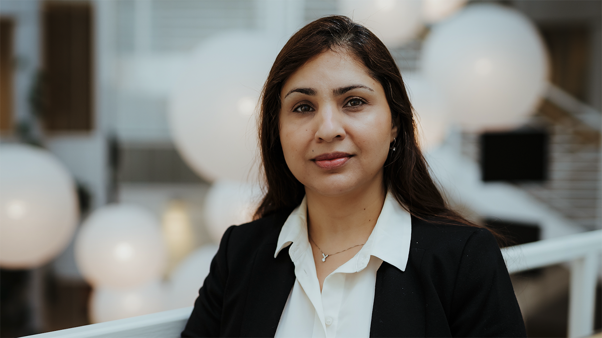 Toktam står på campus med en uskarp bakgrunn som fremhever henne i bildet.