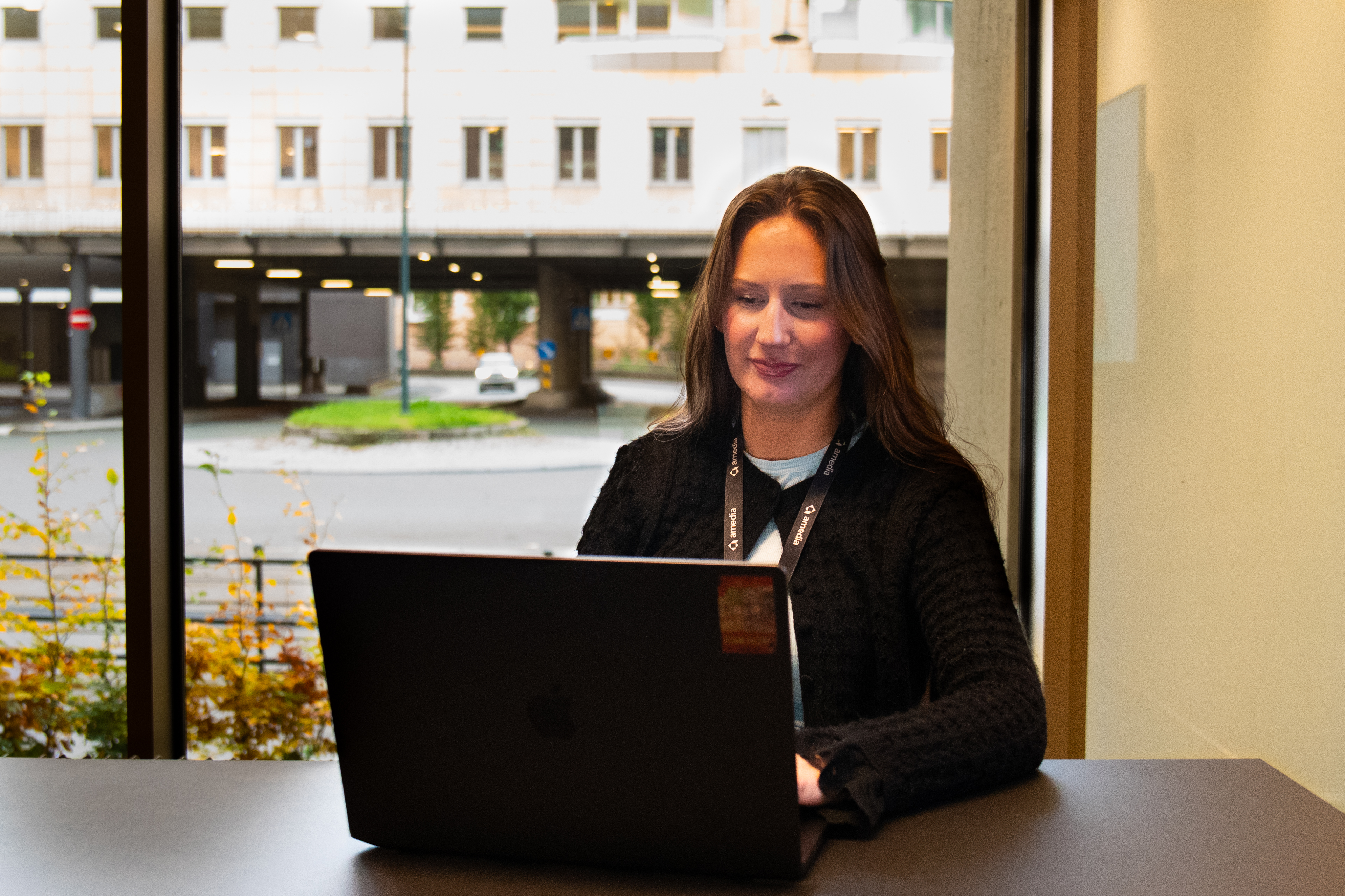 Julie sitter foran sin PC på et møterom og jobber.