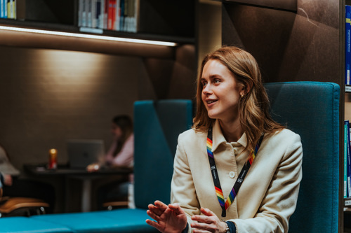 Student på bibliotek snakker til person utenfor bildet.