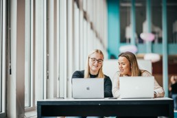 To studenter sitter på et bord med hver sin PC foran seg