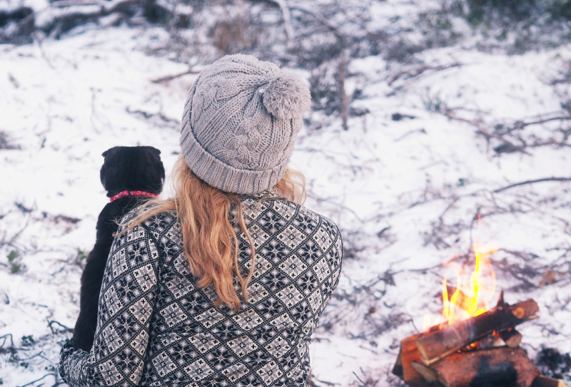 Kvinne med hund som hviler ved et bål