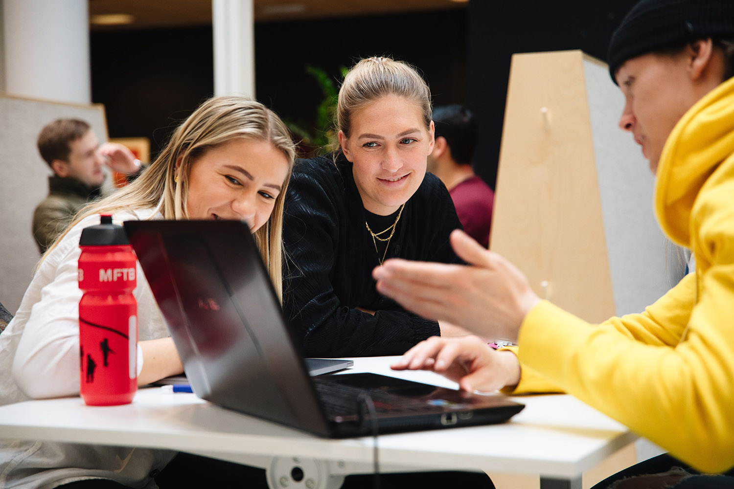 Foto av en mannlig og to kvinnelige studenter som studerer en laptop-skjerm.