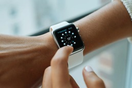 En apple-watch klokke på et håndledd som viser klokkeslett og værvarsel