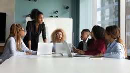 A woman standing up to talk to her co-workers around a table in the office