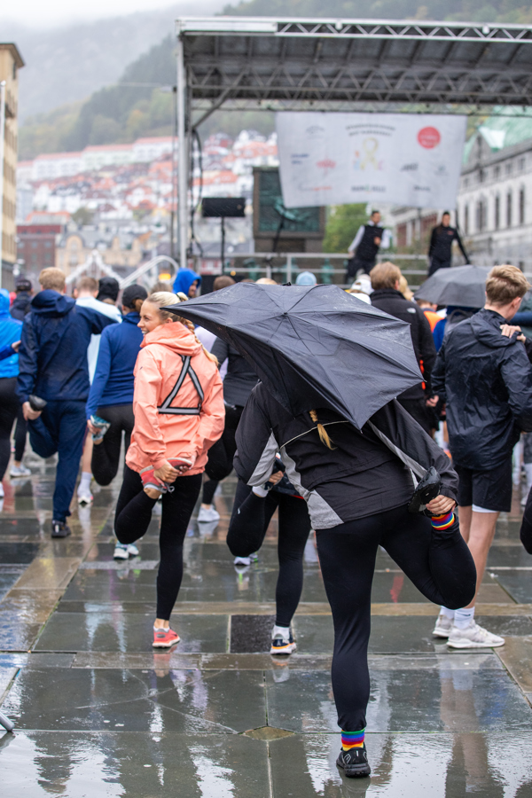 Foto av mennesker som strekker ut på Torgallmenningen, en av dem holder en paraply.