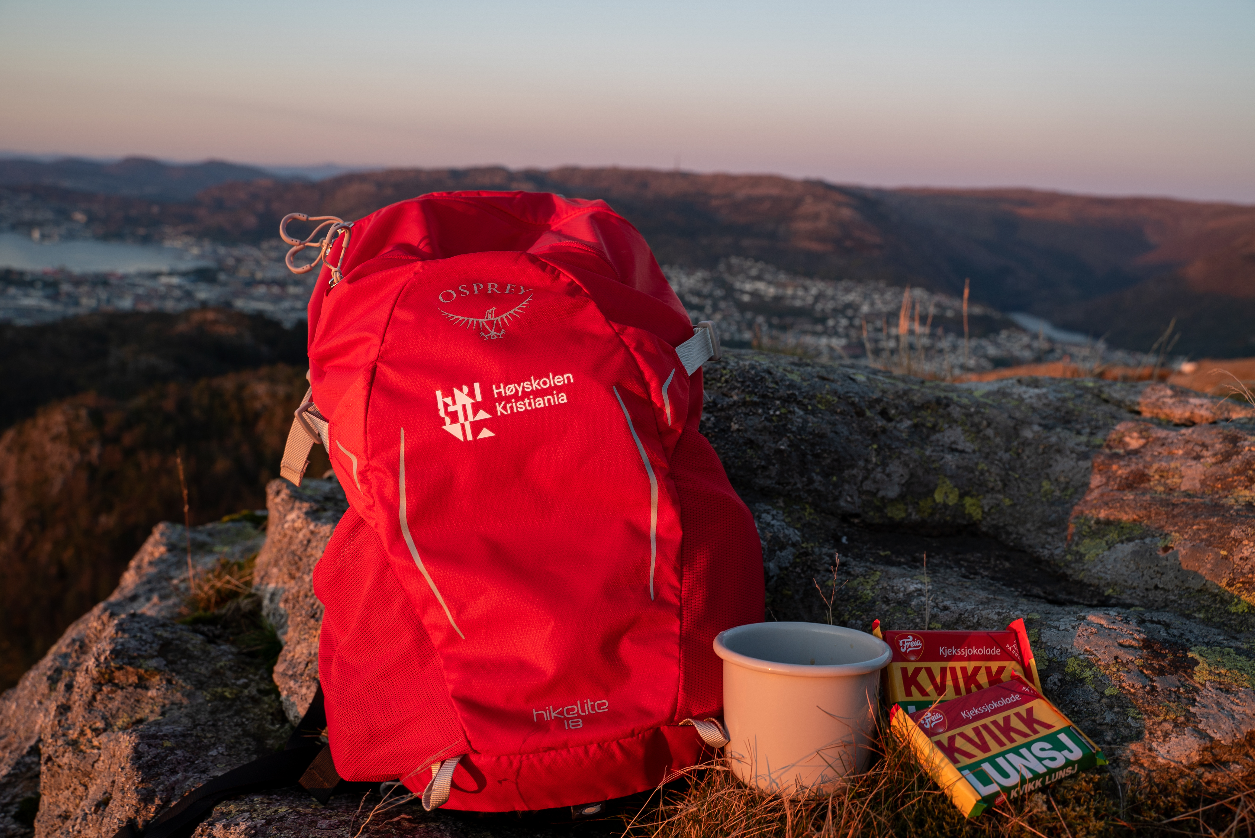 Foto av Kristiania-ryggsekk på fjelltopp, med utsikt over Bergen i bakgrunnen.