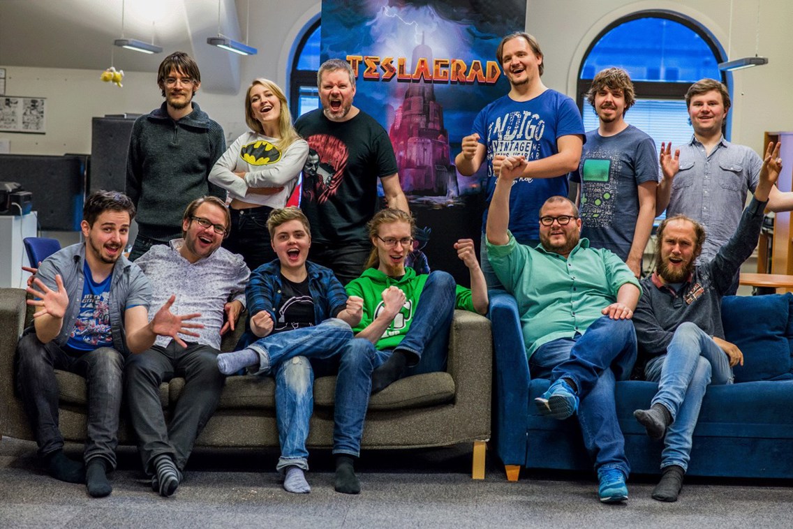 Aslak Helgesen sitter i en sofa og jubler sammen med kollegaene sine i Rain Games AS.
