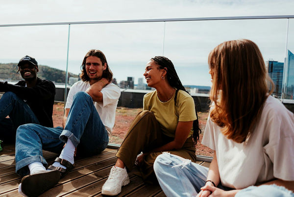 Fire studenter som sitter inntil glassgelenderet på takterrassen til Urtegata i Oslo