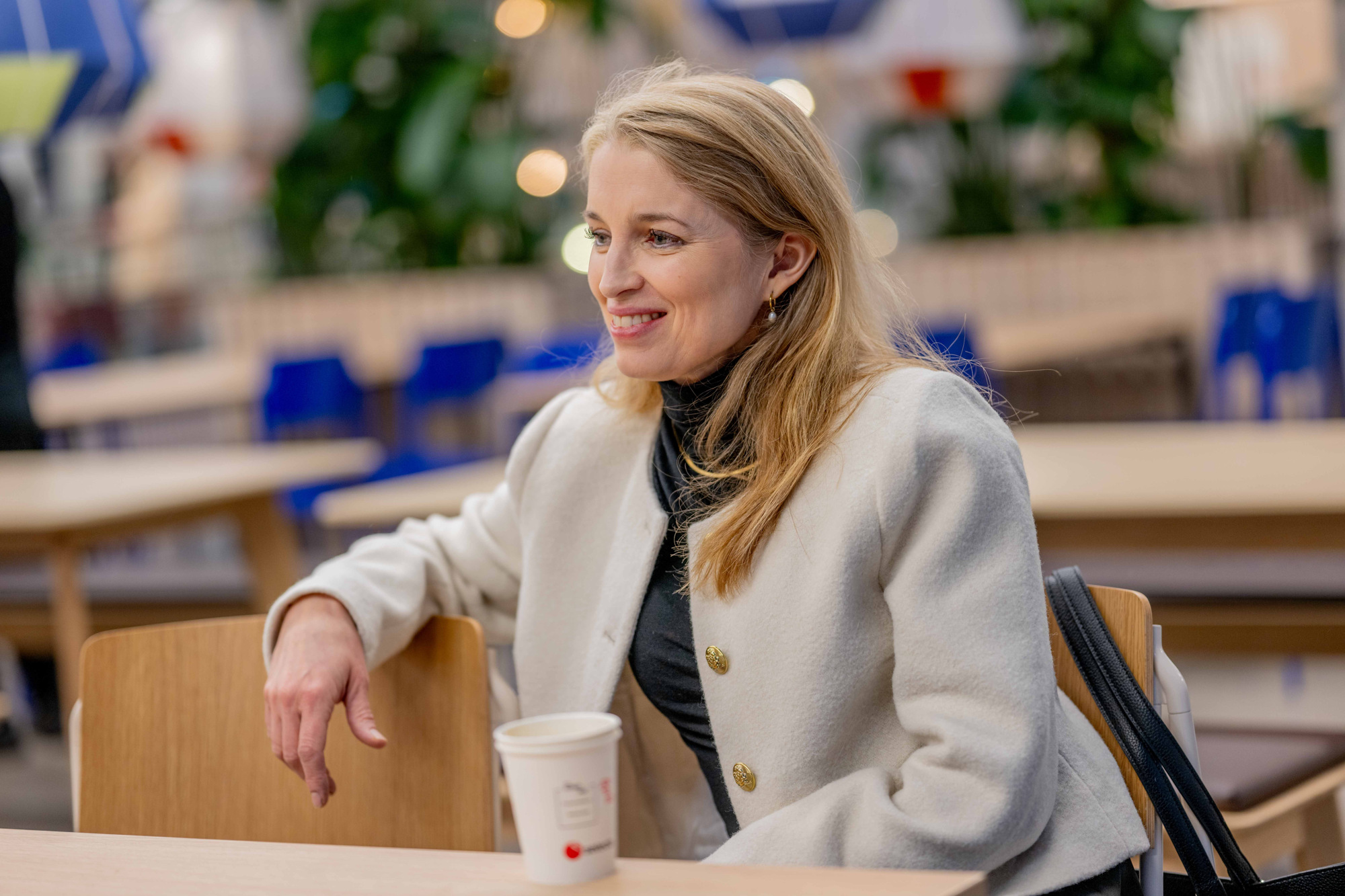 Helene sitter ved et bord i kantinen på campus. 