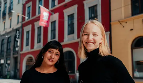 To kvinner smiler foran Kristiania i Kirkegata