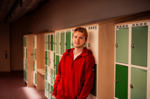 Student står i en gang foran låsbare skap.
