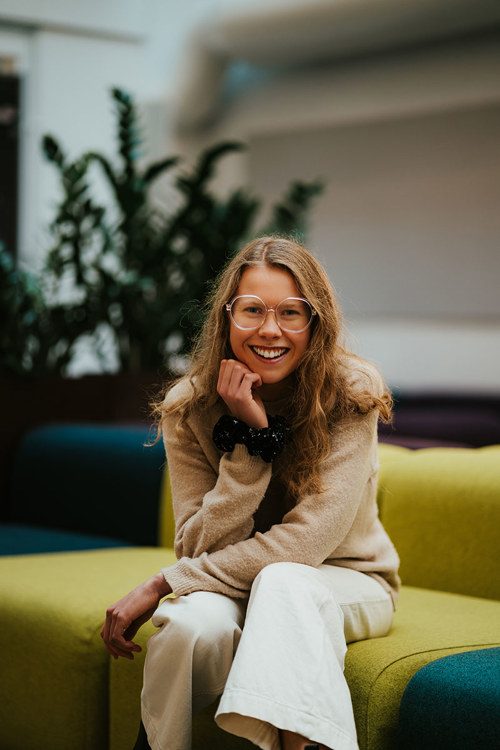 Foto av kvinne med briller som sitter i en sofa