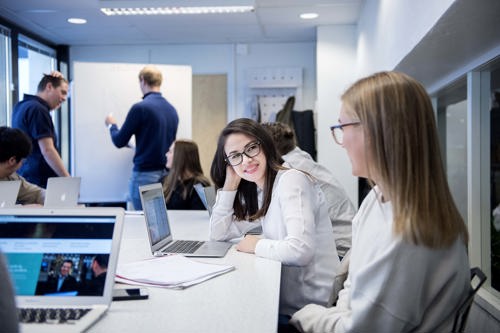 Foto av to kvinnelige studenter i et klasserom.