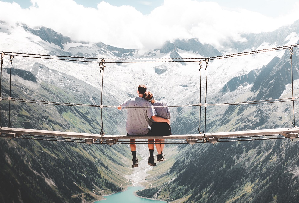 Et par klemmer hverandre på hengebro i fjellet