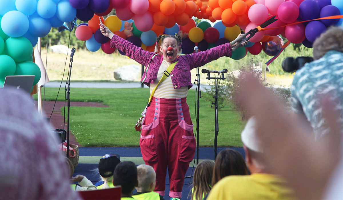 Klovn står foran mange ballonger.