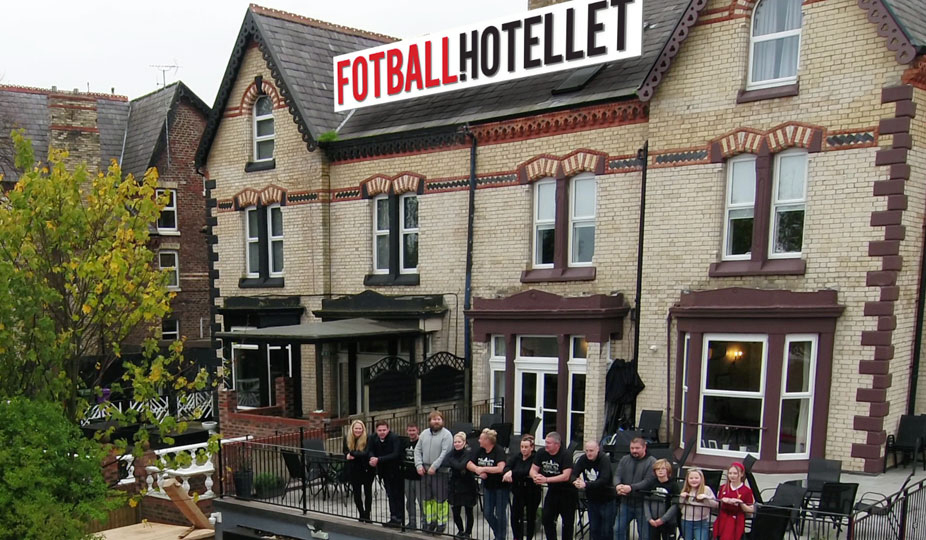 Charlotte Eide har designet logoen til Fotballhotellet som pryder taket til hotellet, en eldre murbygning. På balkongen foran hotellet står en gruppe mennesker på rekke og rad, som lener seg over rekkverket.