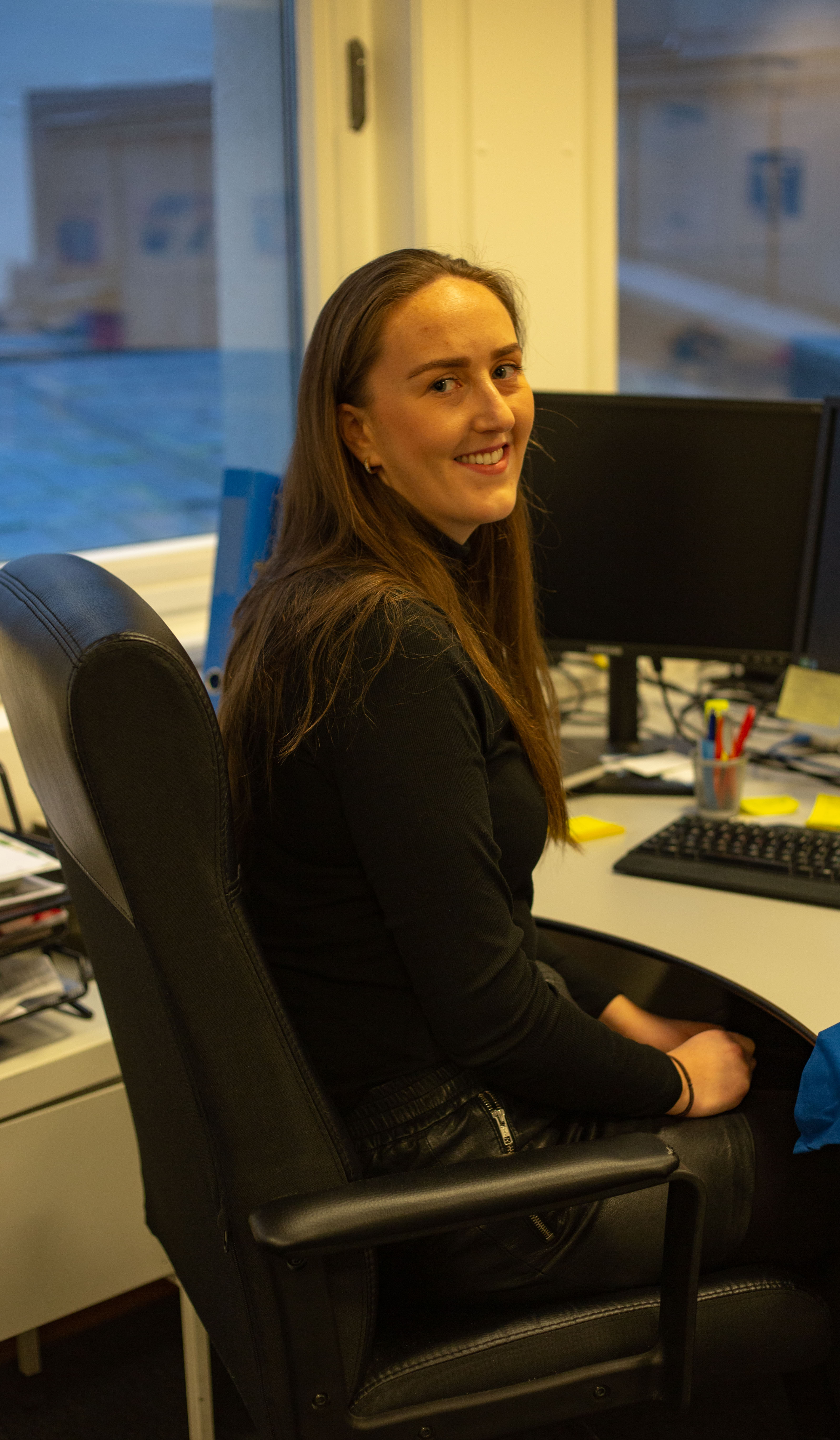 Agnethe Thun Hindbjørgmo har studert prosjektledelse og europastudier. Her sitter hun ved desken på jobb i Europeisk Undgom og smiler mot kamera.