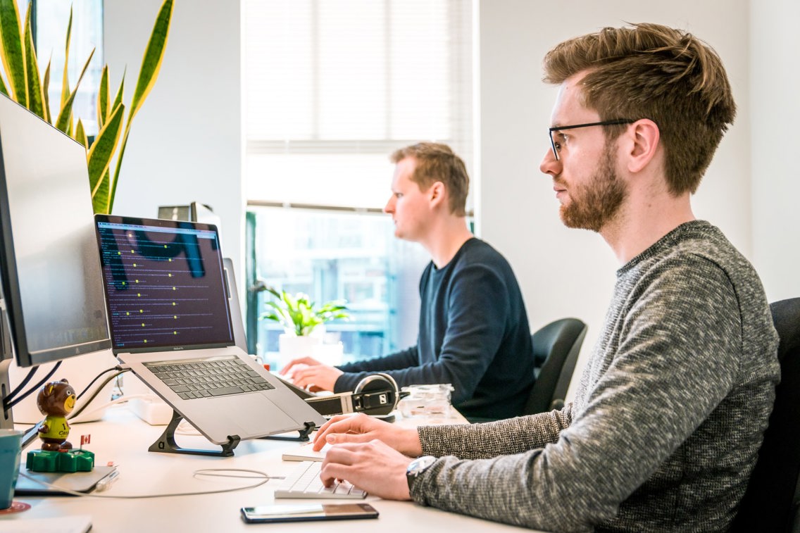 To menn på kontor som jobber med PC.