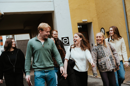 Gruppe studenter går over gaten foran campusbygget.