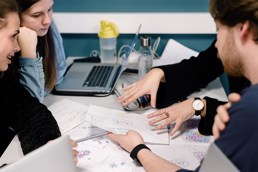 Fire studenter rundt et bord som ser på notater.