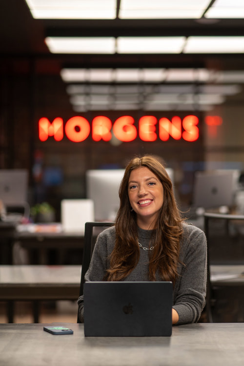 Victoria Ekeli jobber på macen sin inne på kontoret til Morgenstern. I bakgrunnen er Morgensterns logo i neonlys