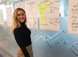 A woman standing in front of a wall with big white papers with writing on them