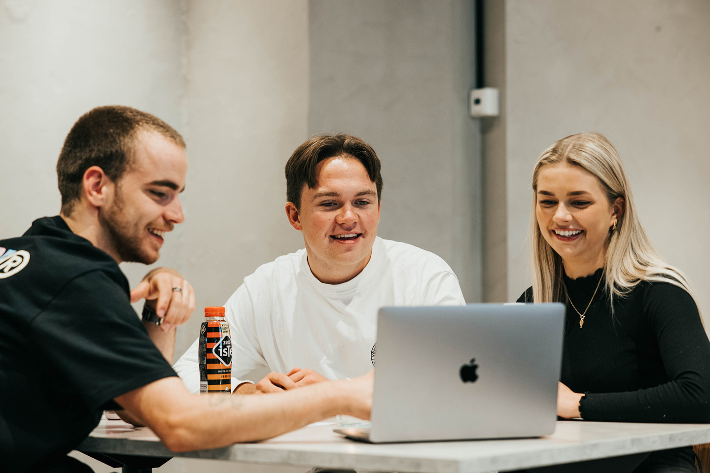 Foto av tre studenter rundt en PC