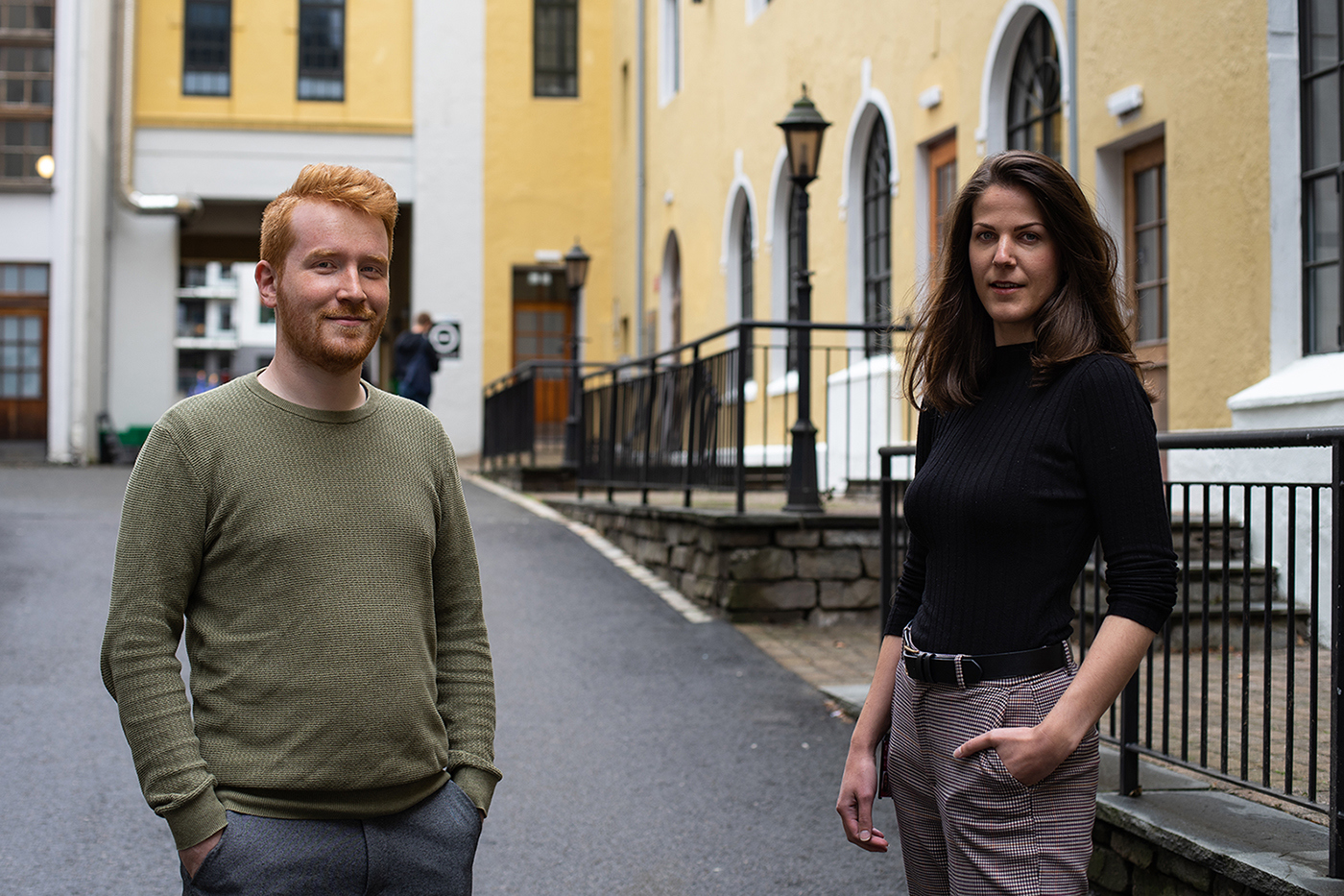 Foto av mann og kvinne foran et stort, gammelt mursteinsbygg.