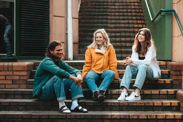 Tre studenter som sitter i en trapp og prater