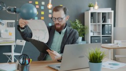 En mann blar gjennom en bunke med ark hvor det står masse statistikker