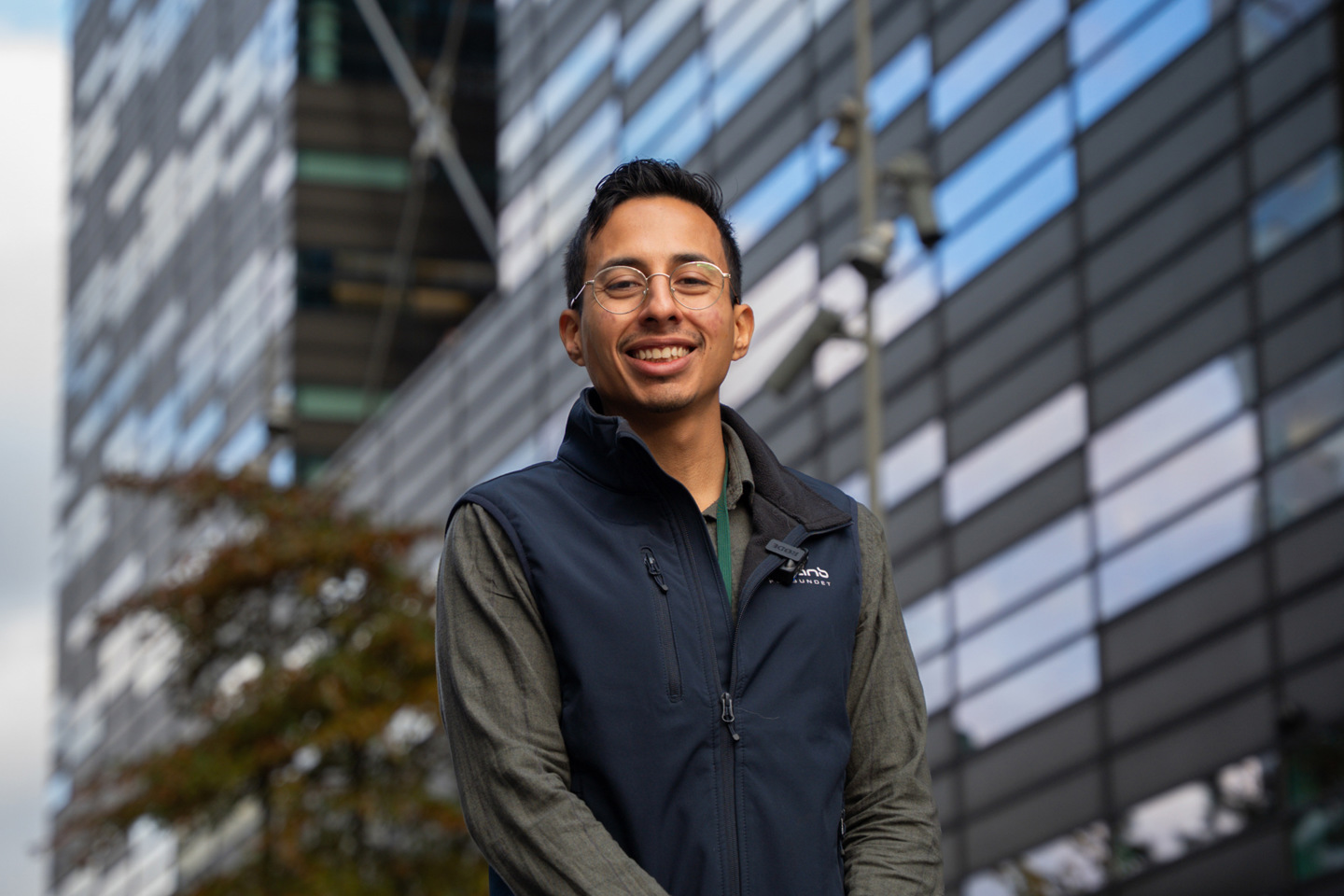 Luis står og smiler med et høyt kontorbygg i bakgrunnen. 