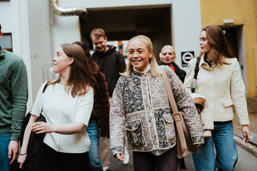 Bildelenke av studenter som går utenfor campusbygg.