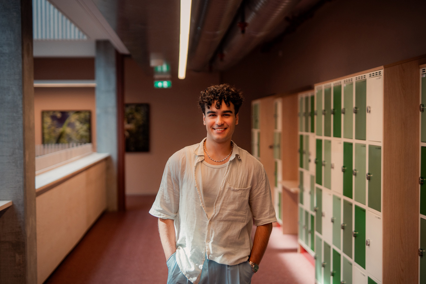 Student står i en gang foran en rekke låsbare skap.