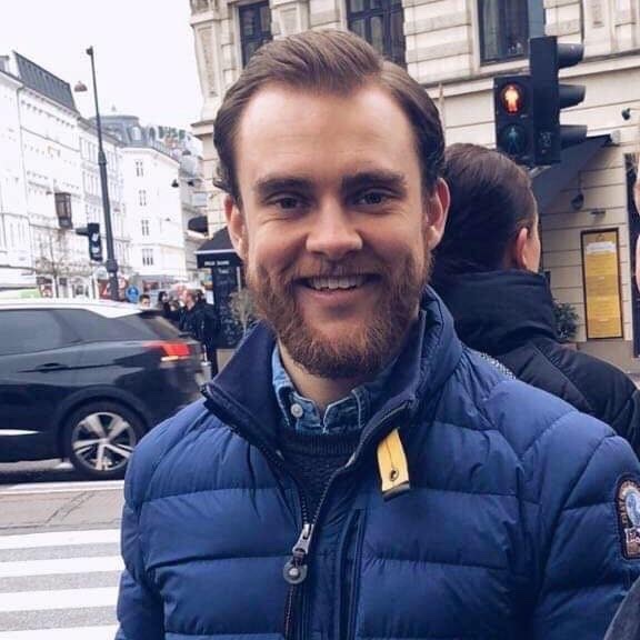 Foto av en mann på gaten som smiler i kamera.